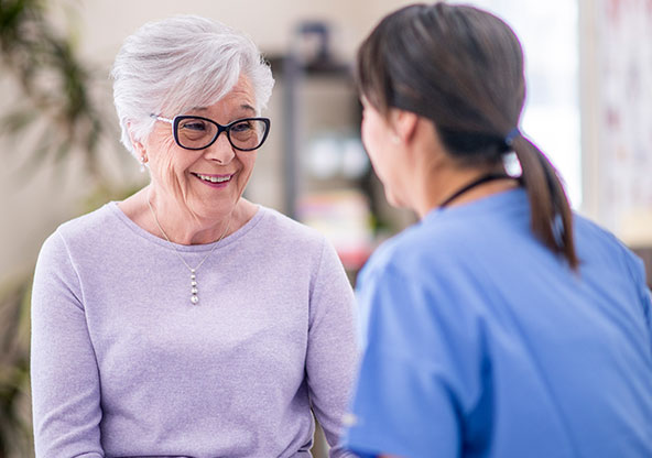 A senior woman smiling and talking to her doctor